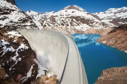 Ein grosser Staudamm in einer schneebedeckten Berglandschaft.